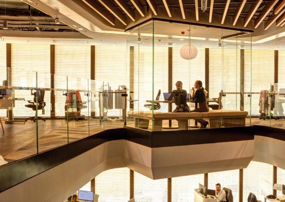 people sitting at a desk in a room with glass walls