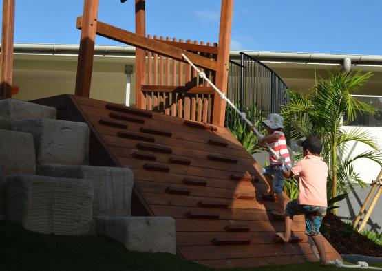 two kids climbing a wooden structure