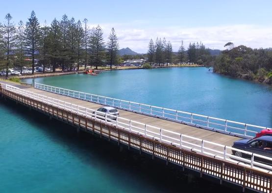 a bridge over water with cars and trees