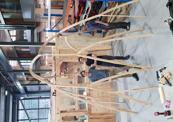 a group of men standing in a room with a wooden structure