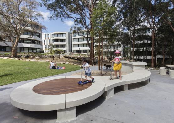 a group of kids riding scooters on a circular platform in a park