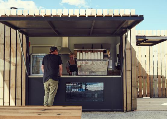 a man and woman standing in front of a small coffee shop