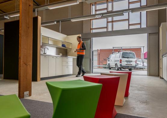 a man in an orange vest standing in a room with colorful stools