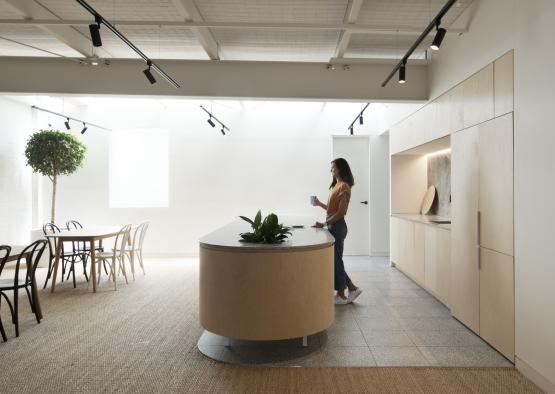 a woman standing in a room with a table and chairs