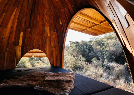 a bed in a wood structure with trees in the background