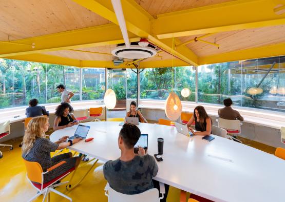 a group of people sitting at tables with laptops