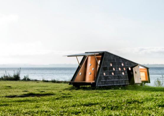 a small house on grass by water