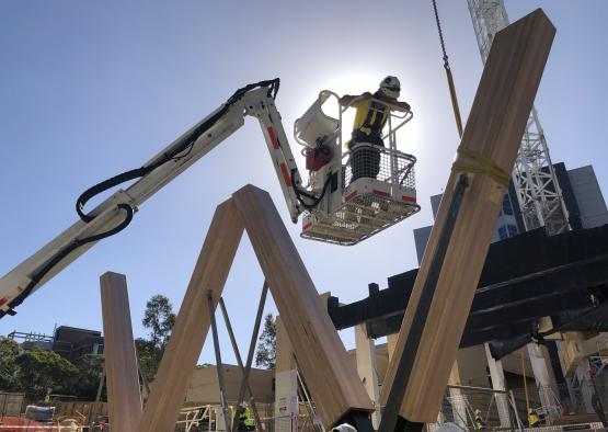 a man in a crane lifting a wooden beam