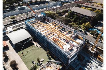 a building under construction with a crane and trees