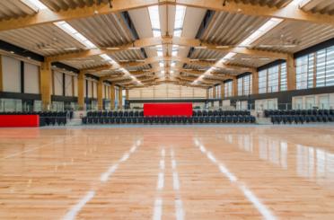 a large indoor gym with a wooden floor and chairs